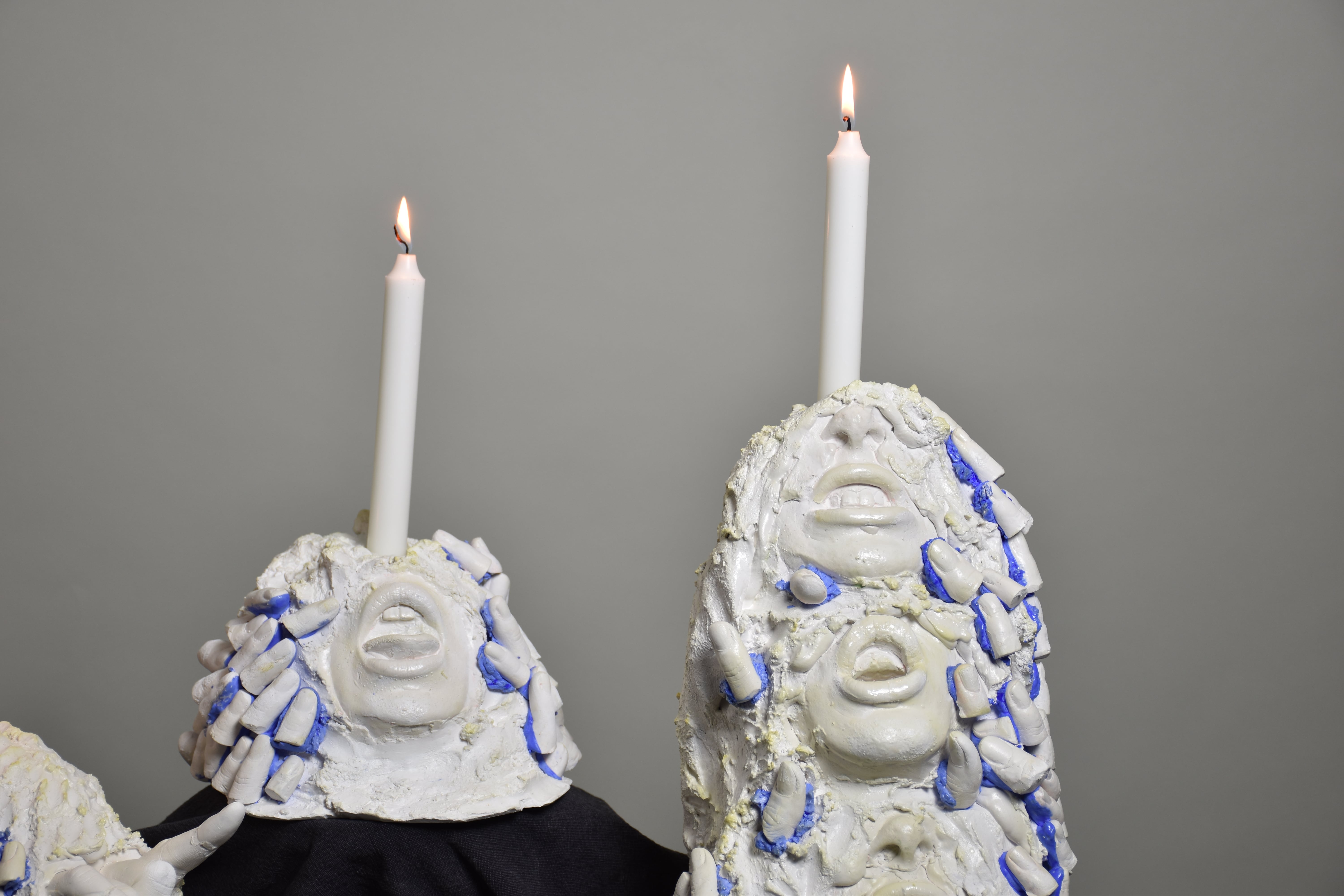 abstract candle holders with open mouths, hands and fingers on it